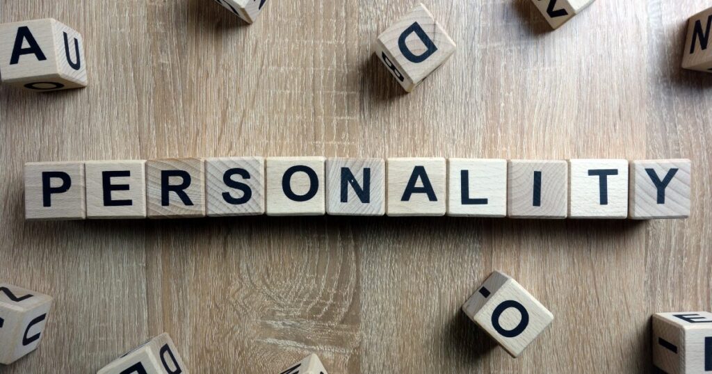 Wooden letter blocks spell'PERSONALITY' on a light wood surface, with other letter blocks scattered around.