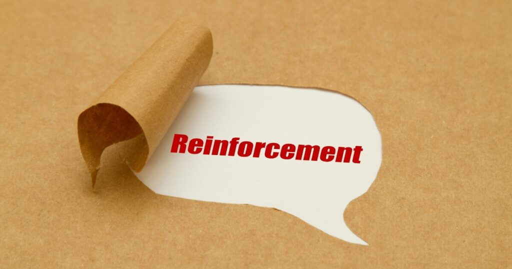 Rolled brown paper reveals a white speech bubble with the red word'Reinforcement'.